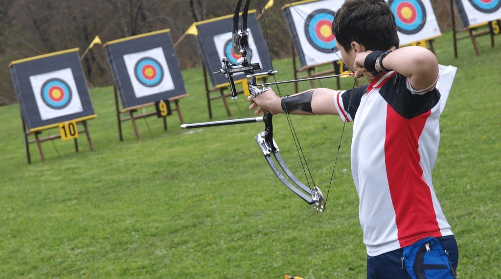 A young man aiming with a compound bow.