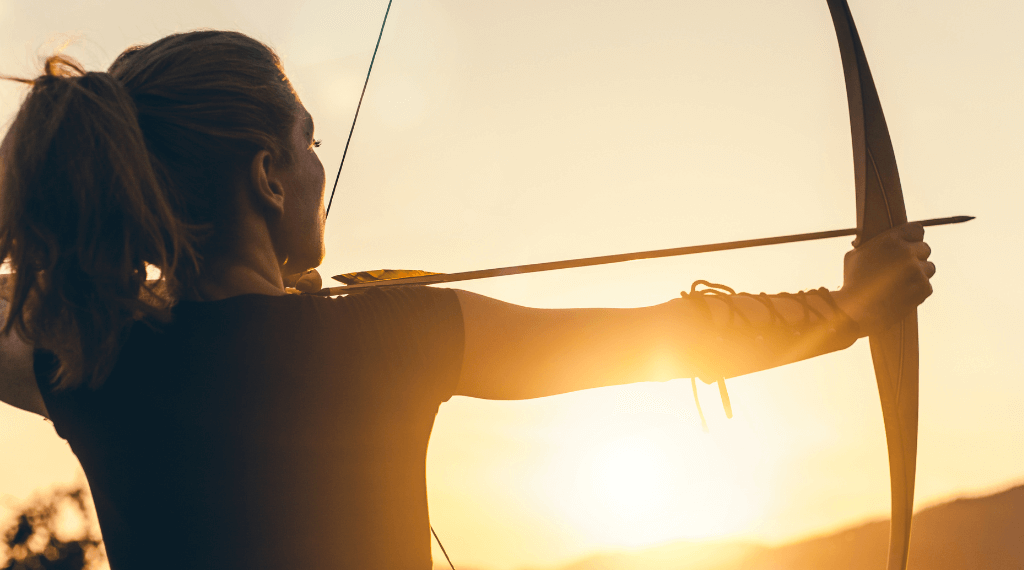 A woman shooting a traditional longbow.