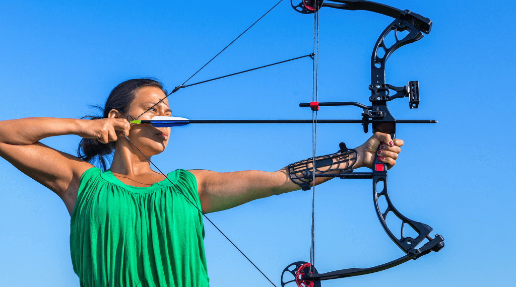 A young woman shooting with a compound bow.