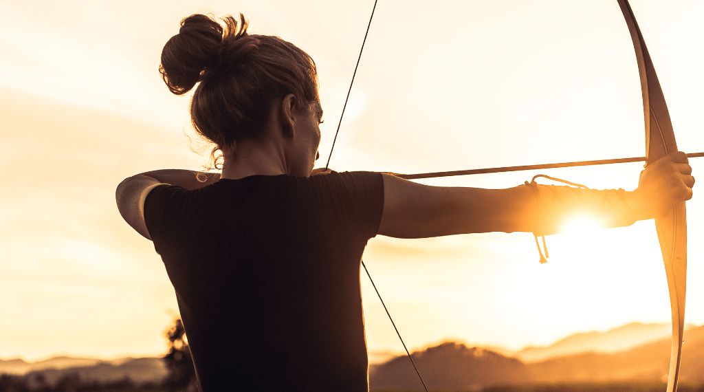A woman shooting with a longbow.